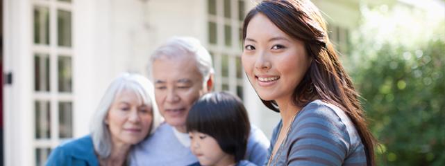 An Asian woman in the forground with a child and an older man and woman in the background.